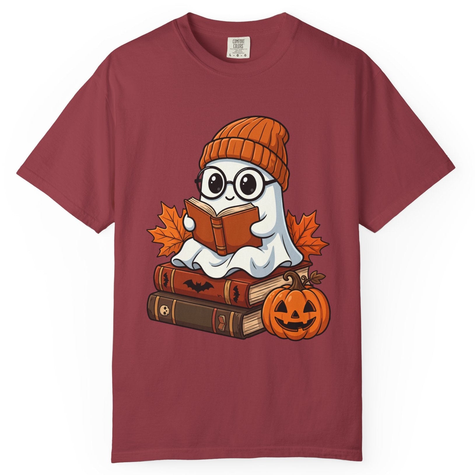 A chilli short-sleeve crewneck t-shirt featuring a cartoon graphic of a ghost wearing glasses and an orange knit beanie, sitting on a stack of books and reading a book next to a jack-o'-lantern pumpkin and autumn leaves.