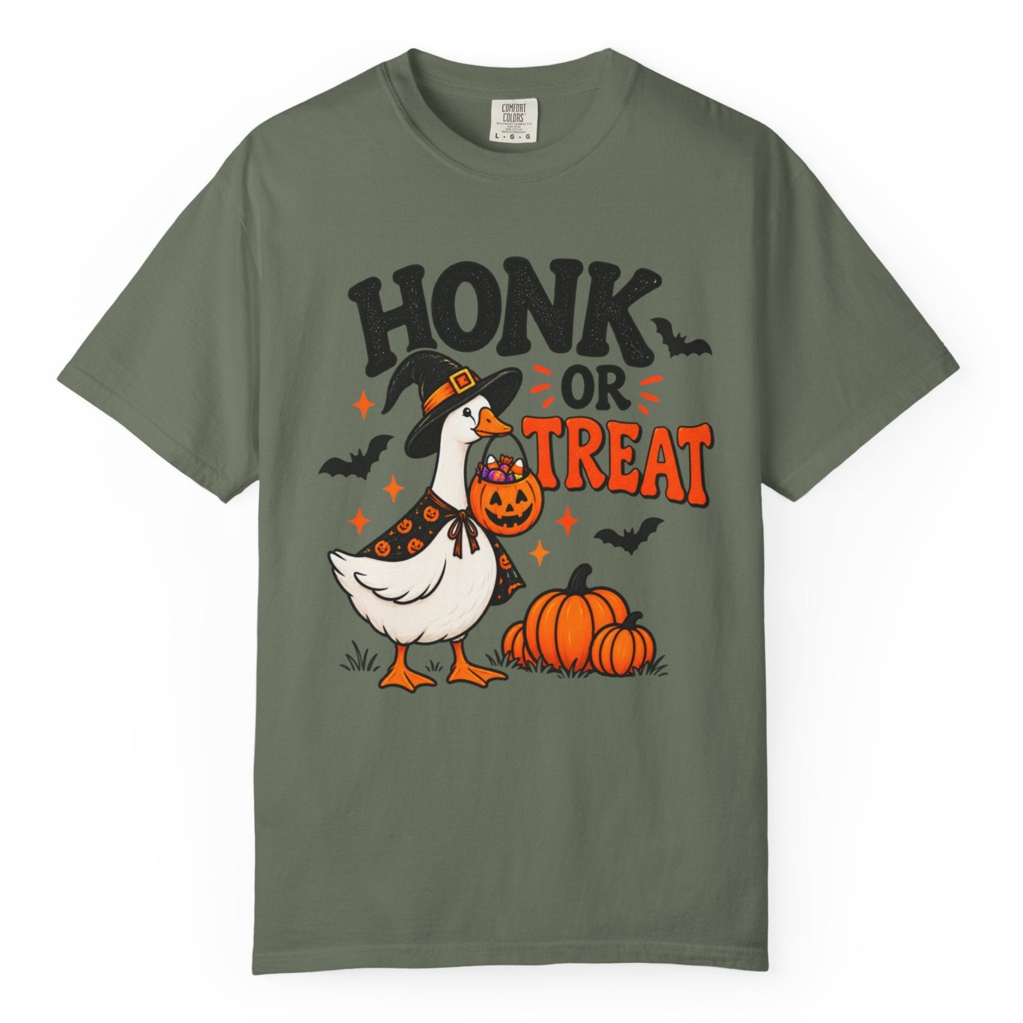 A light green short-sleeve crewneck t-shirt featuring a Halloween graphic of a goose dressed as a witch holding a jack-o'-lantern next to pumpkins, with the text 'HONK OR TREAT'