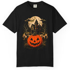 A black short-sleeve crewneck t-shirt featuring a detailed Halloween graphic print on the front. The graphic depicts a glowing orange jack-o'-lantern pumpkin in the foreground, with a spooky haunted house, bare trees, bats, and a full moon in the background.