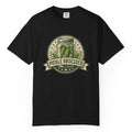 A black short-sleeve t-shirt hanging on a wooden hanger against a light wood pegboard wall. The shirt features a circular graphic print with a jar of pickled green onions and the words 'PICKLE OBSESSED' in a banner.