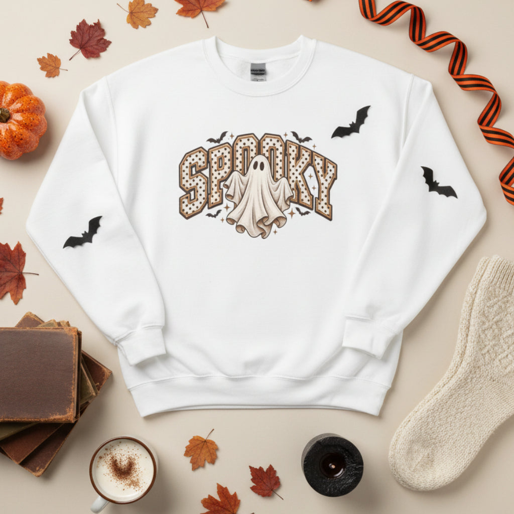 A white crewneck sweatshirt featuring a 'Spooky' Halloween graphic on the front with a ghost, bats, and brown polka-dot lettering, shown against a plain white background.