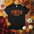 A black short-sleeve crewneck t-shirt with 'PUMPKIN SEASON' printed on the chest in distressed orange lettering, displayed with fall accessories