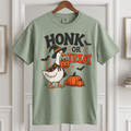 A Bay shrt Honk or Treat Halloween goose wearing a witch hat and pumpkin cape, holding a jack-o-lantern candy bucket with pumpkins and bats
