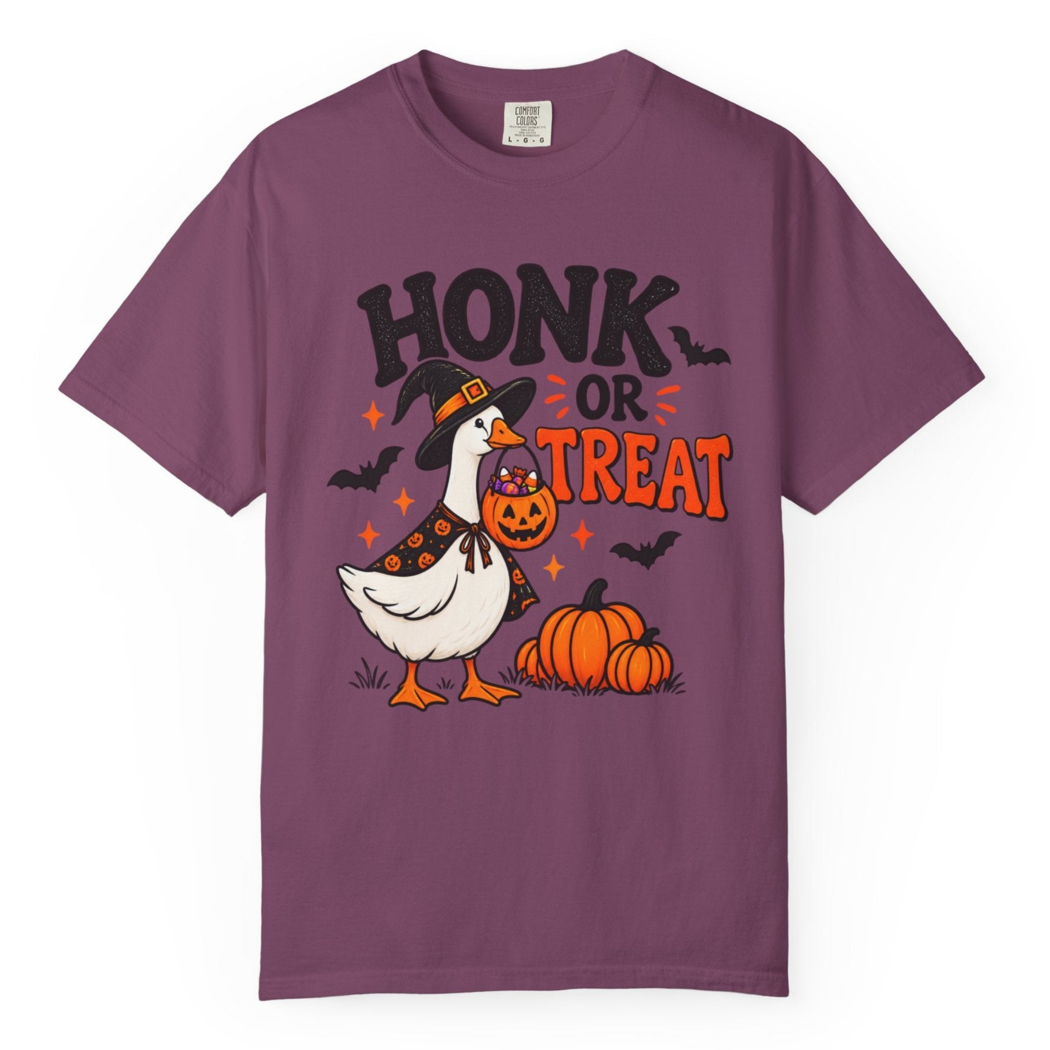 A purple short-sleeve crewneck t-shirt featuring a Halloween graphic of a goose in a witch hat next to pumpkins with the text 'HONK OR TREAT'.