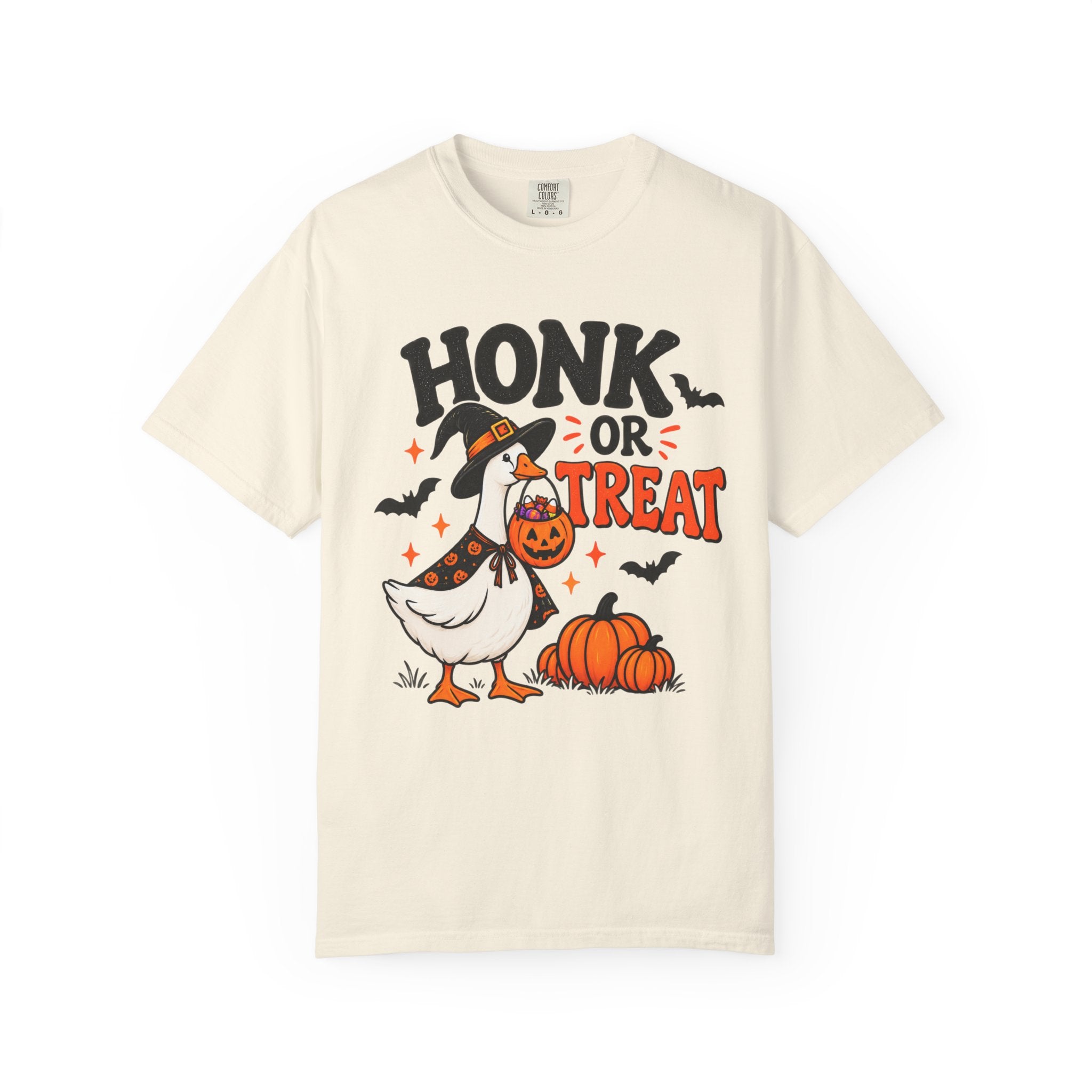 An off-white short-sleeve t-shirt with a Halloween graphic featuring a goose in a witch hat, pumpkins, bats, and the text 'HONK OR TREAT'.