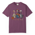 A purple short-sleeve crewneck t-shirt featuring a graphic print of three geese dressed in Halloween costumes (as mummy, skeleton, and in blue overalls), set against a plain white background.