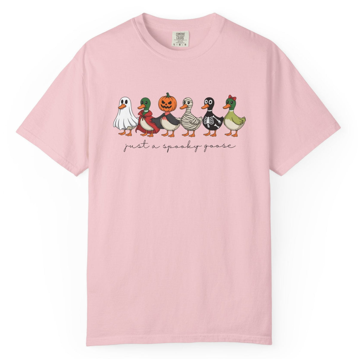 A light pink short-sleeve crewneck t-shirt featuring a graphic of six cute ducks dressed in Halloween costumes with the text 'just a spooky goose' printed below them