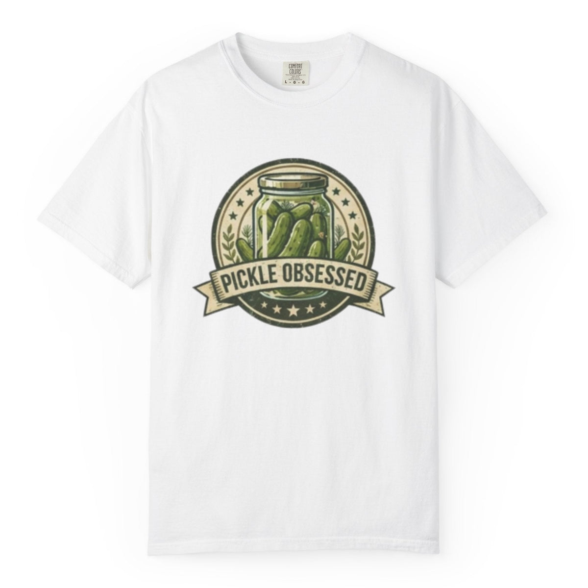 A white short-sleeve t-shirt hanging on a wooden hanger against a light wood pegboard wall. The shirt features a circular graphic print with a jar of pickled green onions and the words 'PICKLE OBSESSED' in a banner.