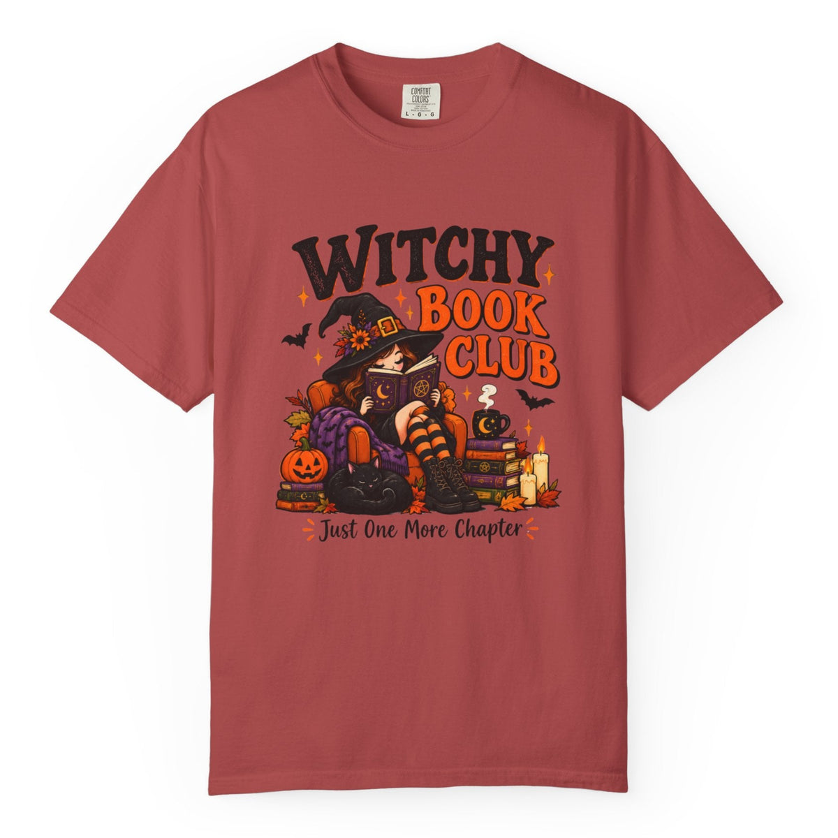 A dusty rose red short-sleeve t-shirt with a Halloween-themed graphic on the front that reads 'WITCHY BOOK CLUB' and 'Just One More Chapter'. The graphic features a cartoon witch, a pumpkin, a candle, and a potion bottle.