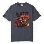 A navy blue crewneck t-shirt featuring a colorful graphic print on the front with the text 'WITCHY BOOK CLUB' and a Halloween-themed illustration of a witch, pumpkins, and candles.