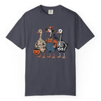 A navy crewneck t-shirt featuring a colorful graphic of three cartoon geese in Halloween costumes (mummy, farmer boy, and skeleton) standing next to a jack-o'-lantern pumpkin.