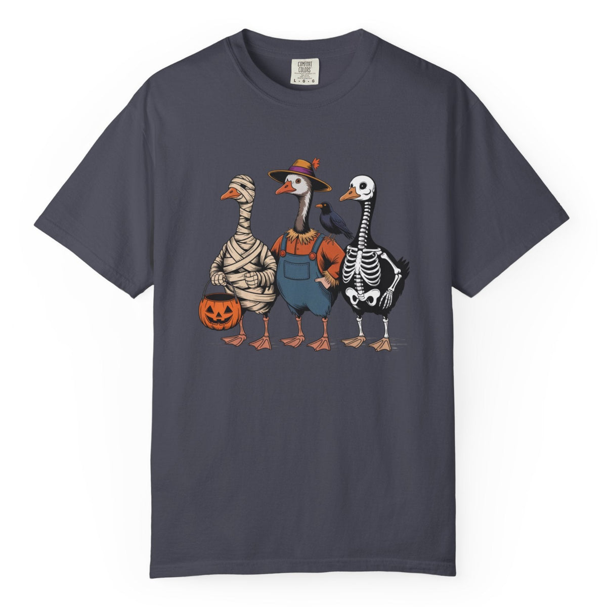 A navy crewneck t-shirt featuring a colorful graphic of three cartoon geese in Halloween costumes (mummy, farmer boy, and skeleton) standing next to a jack-o'-lantern pumpkin.
