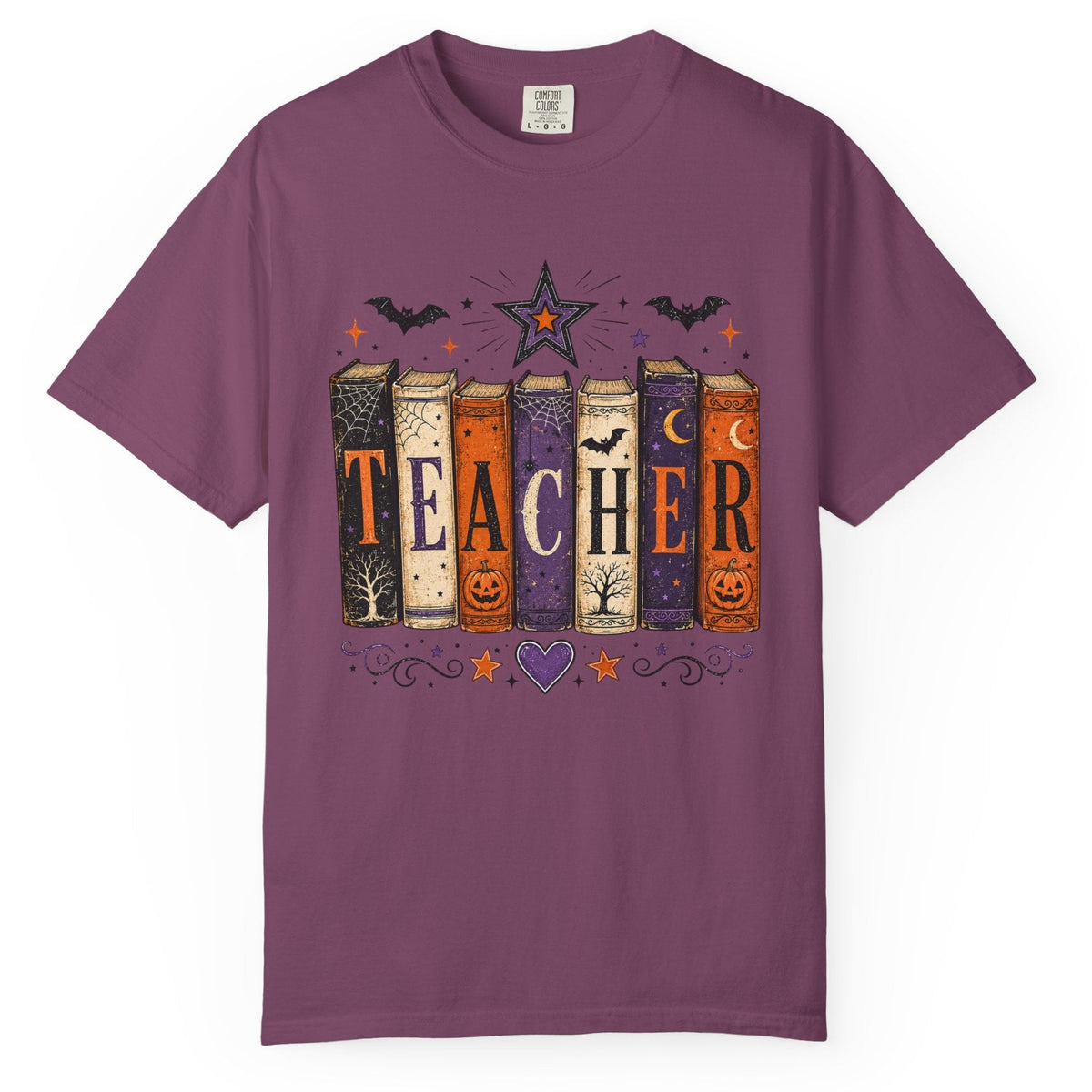 A purple short-sleeve crewneck t-shirt featuring a Halloween-themed graphic of colorful books spelling 'TEACHER' with bats, stars, and pumpkins.
