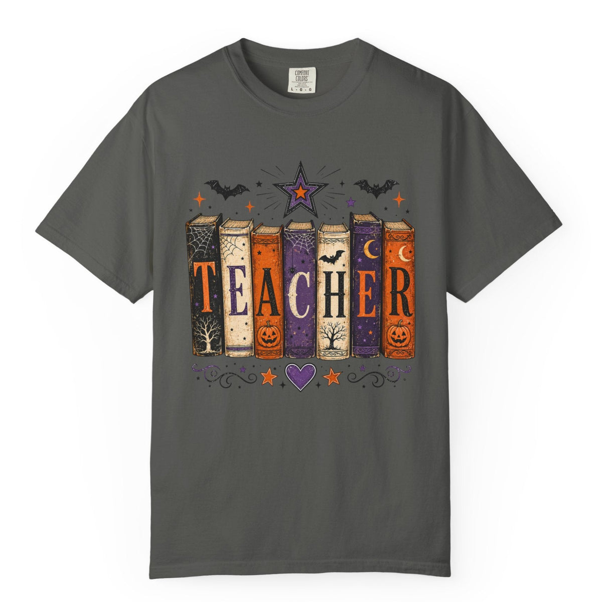 A dark gray short-sleeve crewneck t-shirt featuring a Halloween-themed graphic of six books spelling 'TEACHER' with spooky illustrations like bats, stars, pumpkins, and a purple heart.