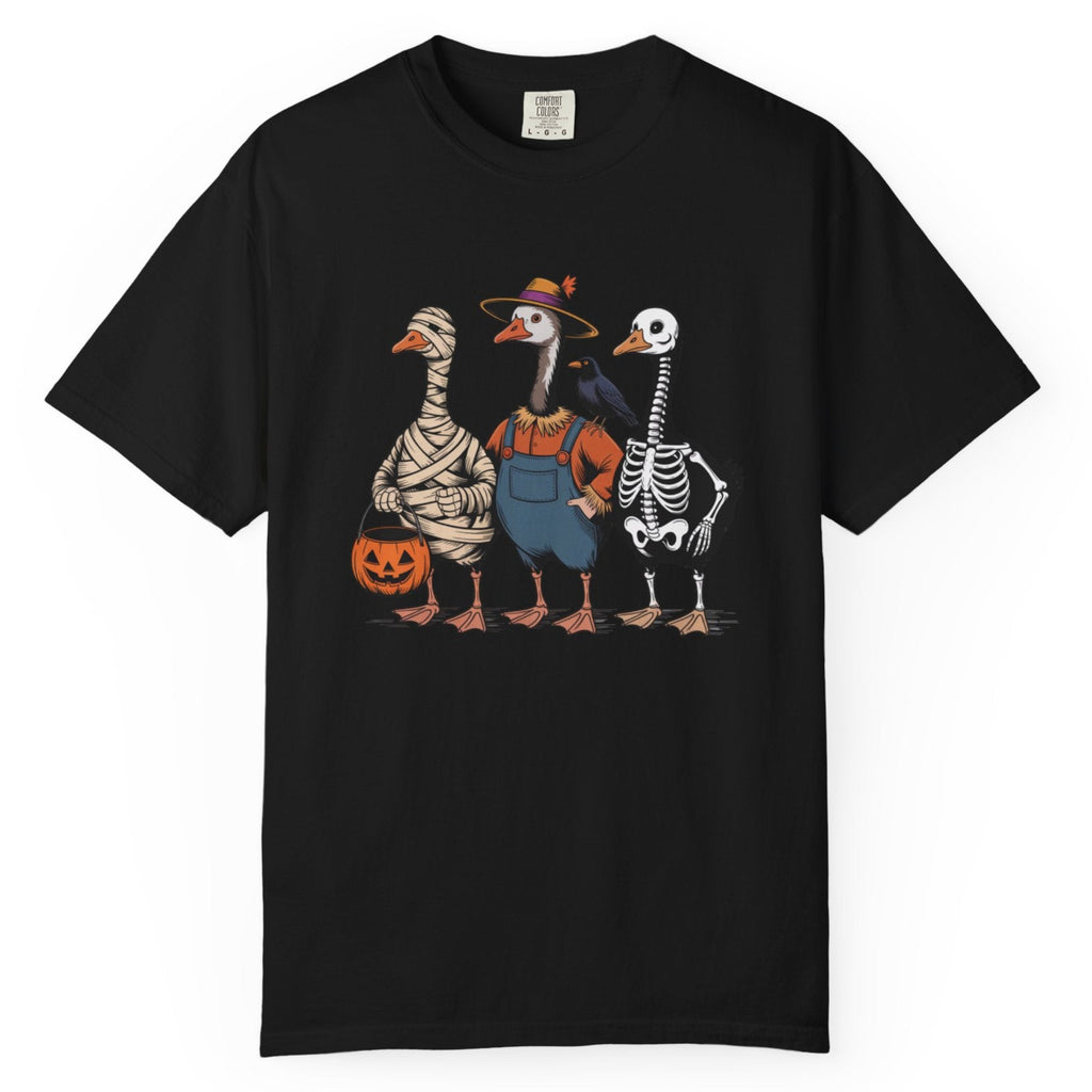 A black short-sleeve crewneck t-shirt featuring a colorful graphic of three geese dressed in Halloween costumes (as a mummy, a farmer, and a skeleton) standing together and holding a jack-o'-lantern.