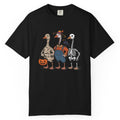 A black short-sleeve crewneck t-shirt featuring a colorful graphic of three geese dressed in Halloween costumes (as a mummy, a farmer, and a skeleton) standing together and holding a jack-o'-lantern.