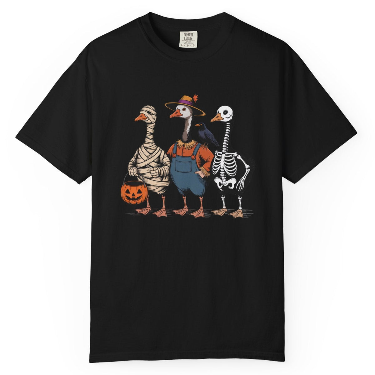 A black short-sleeve crewneck t-shirt featuring a colorful graphic of three geese dressed in Halloween costumes (as a mummy, a farmer, and a skeleton) standing together and holding a jack-o'-lantern.