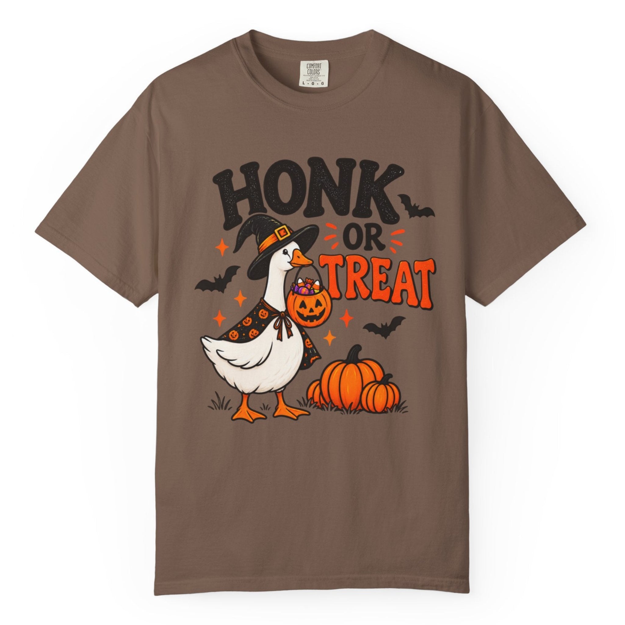 A brown short-sleeve crewneck t-shirt featuring a Halloween graphic of a goose dressed as a witch holding a jack-o'-lantern next to pumpkins, with the text 'HONK OR TREAT'.