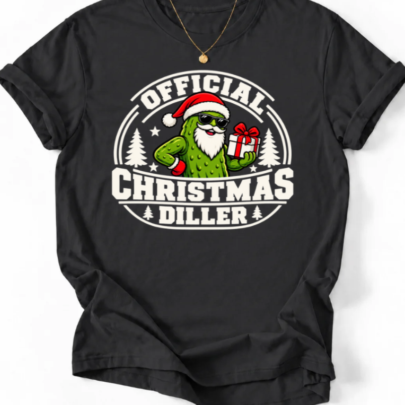 Black Official Christmas Diller graphic T-shirt design featuring a green pickle Santa wearing sunglasses and holding a Christmas present, with festive trees and bold holiday lettering.