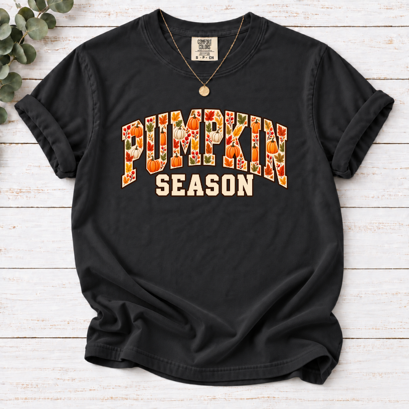 Black T-shirt with Pumpkin Season lettering filled with orange and white pumpkins and autumn leaves.