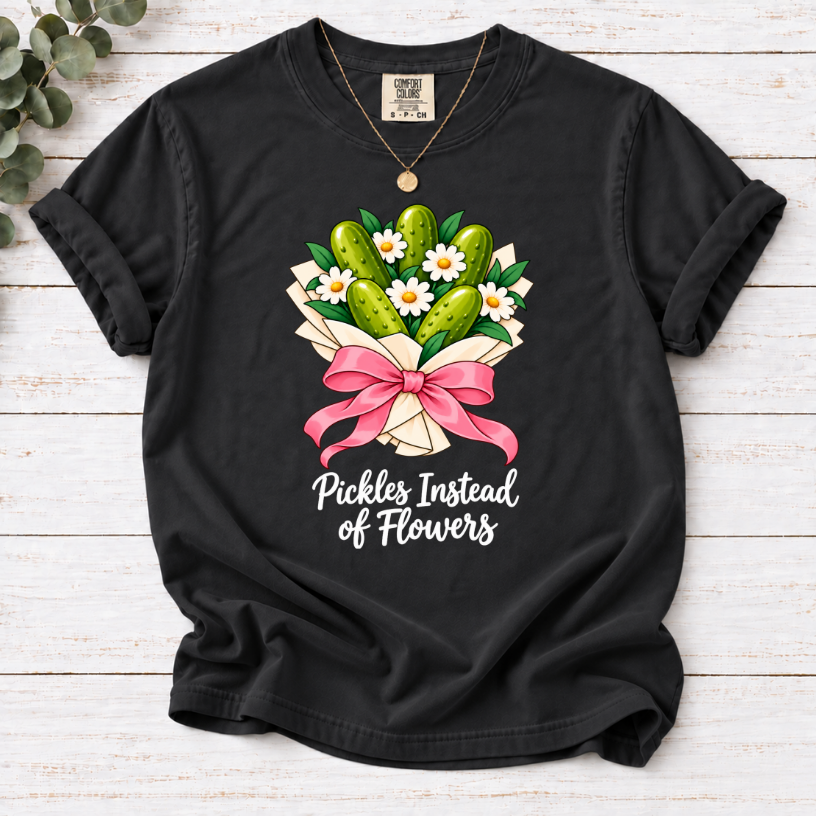 Black T-shirt with a pickle and daisy bouquet, pink bow, and white ‘Pickles Instead of Flowers’ lettering