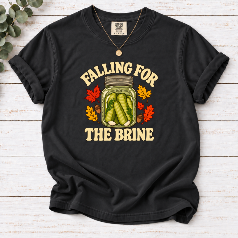 Black T-shirt with “Falling for the Brine” lettering and a pickle jar surrounded by autumn leaves and acorns.