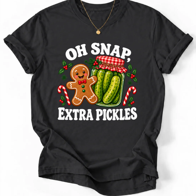 Black T-shirt with “Oh Snap, Extra Pickles” lettering, a smiling gingerbread character, and a pickle jar surrounded by candy canes and holly.