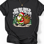 Black T-shirt with “Ho Ho Hold the Pickles” lettering and a pickle dressed as Santa carrying a sack of pickle jars beside snowy trees.
