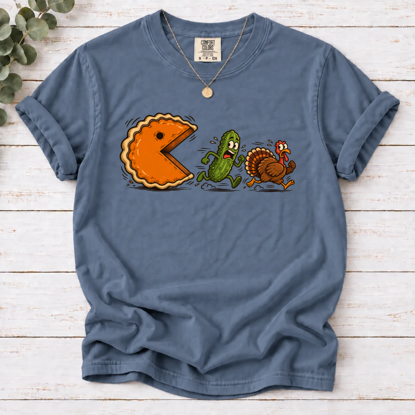 Blue Jean T-shirt featuring a cartoon pumpkin pie chasing a frightened pickle and turkey.