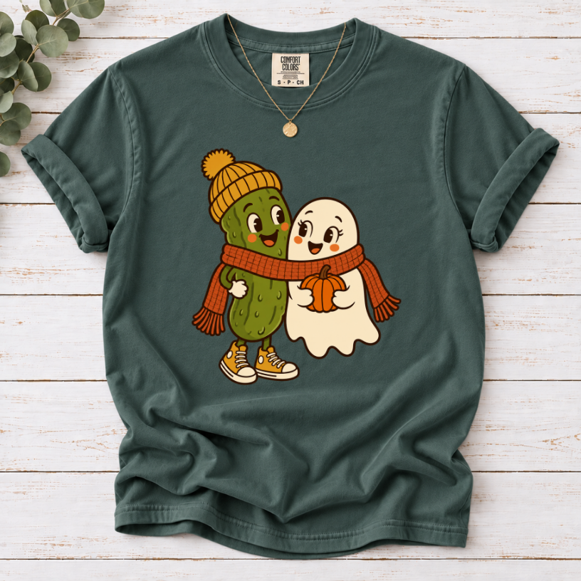 blue spruce T-shirt featuring a smiling pickle in a yellow beanie beside a ghost holding a pumpkin, sharing an orange scarf.”