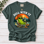 Blue Spruce Dill With It T-shirt featuring a pickle in sunglasses relaxing in a camp chair beside a lake at sunset.