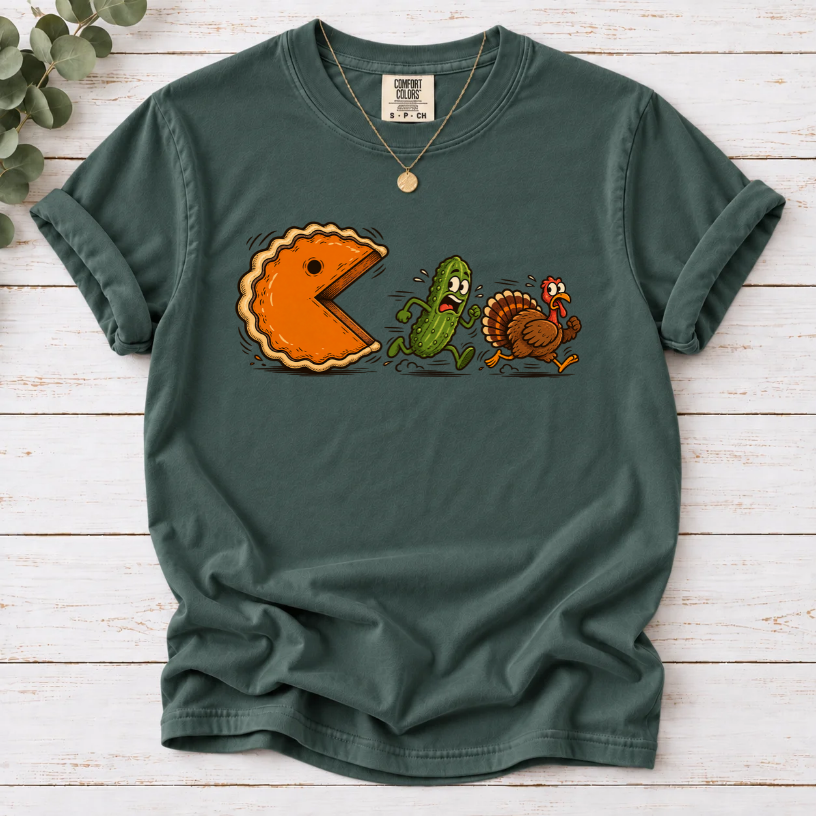 Blue Spruce T-shirt featuring a cartoon pumpkin pie chasing a frightened pickle and turkey.