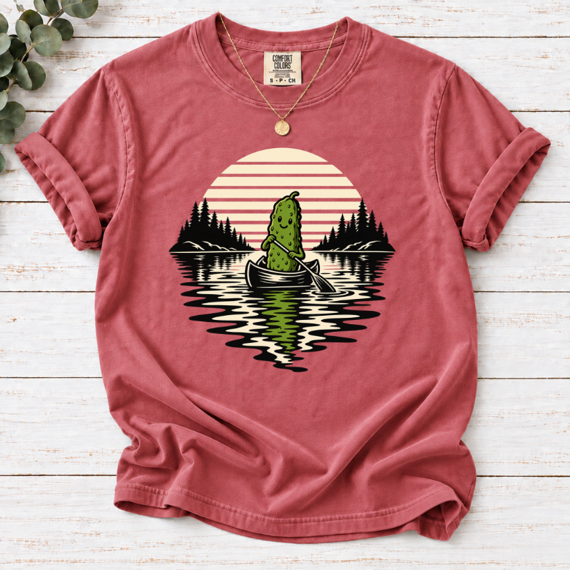Canoeing pickle under a retro sunset on a Crimson T-shirt.