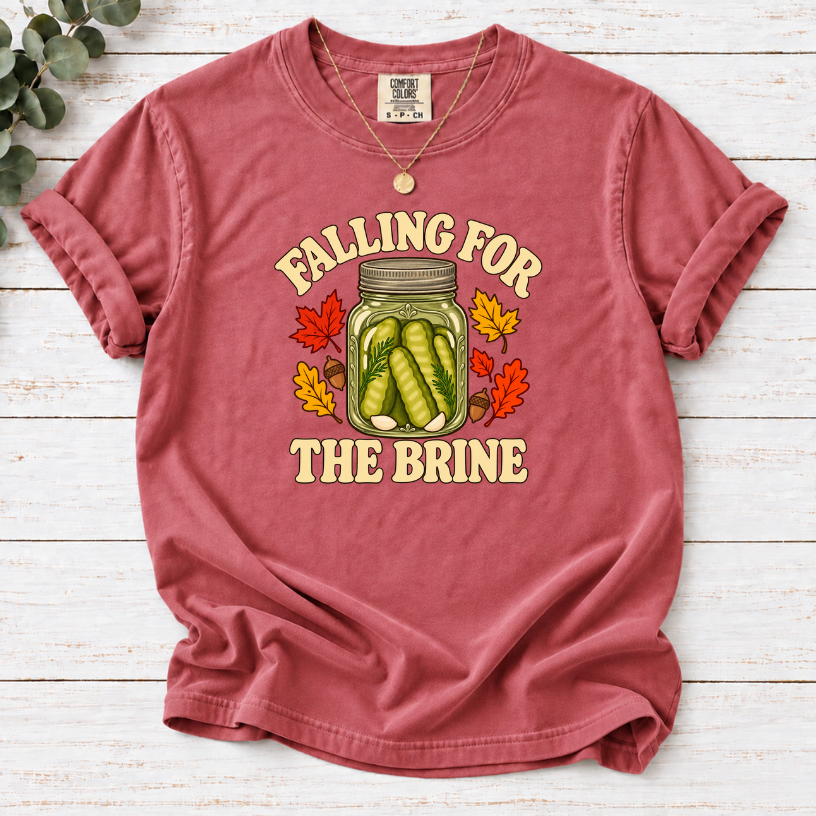 Crimson T-shirt with “Falling for the Brine” lettering and a pickle jar surrounded by autumn leaves and acorns.