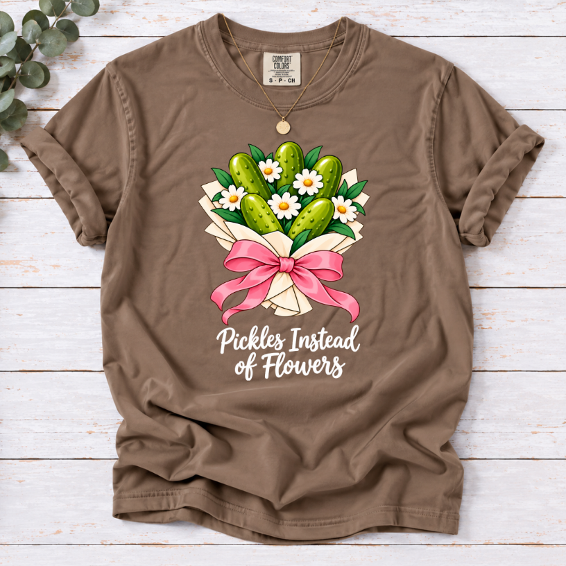Espresso T-shirt with a pickle and daisy bouquet, pink bow, and white ‘Pickles Instead of Flowers’ lettering