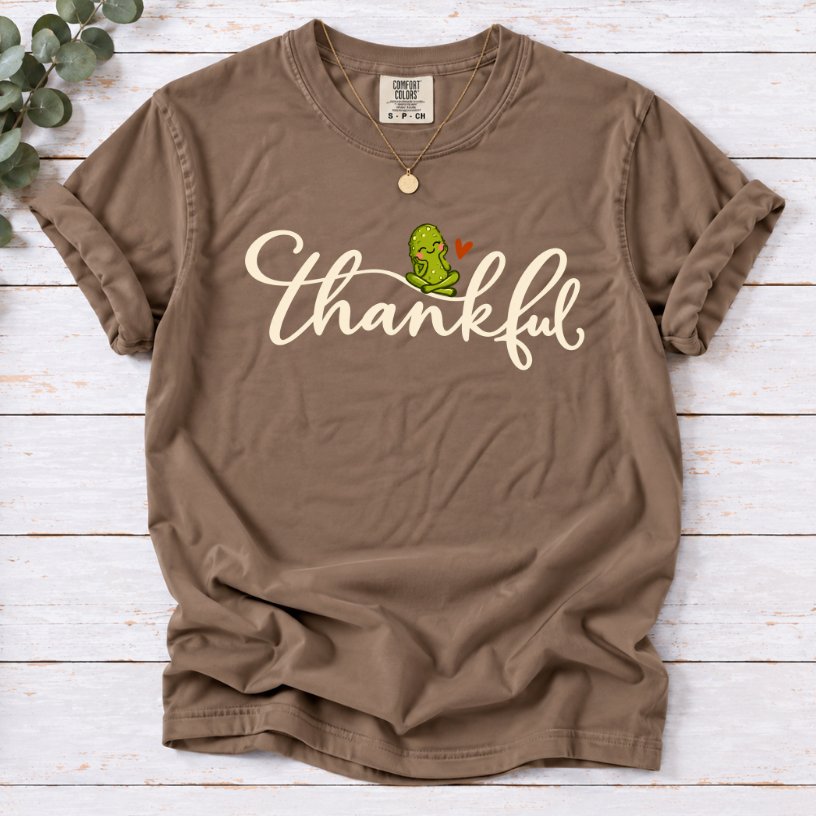 Espresso T-shirt with thankful script, a smiling green pickle, and a small orange heart.