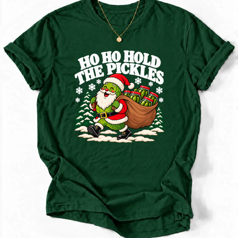 Forest Green T-shirt with “Ho Ho Hold the Pickles” lettering and a pickle dressed as Santa carrying a sack of pickle jars beside snowy trees.