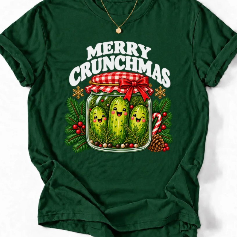 Forest Green T-shirt with “Merry Crunchmas” lettering above three smiling pickles in a jar decorated with a red bow and Christmas greenery.