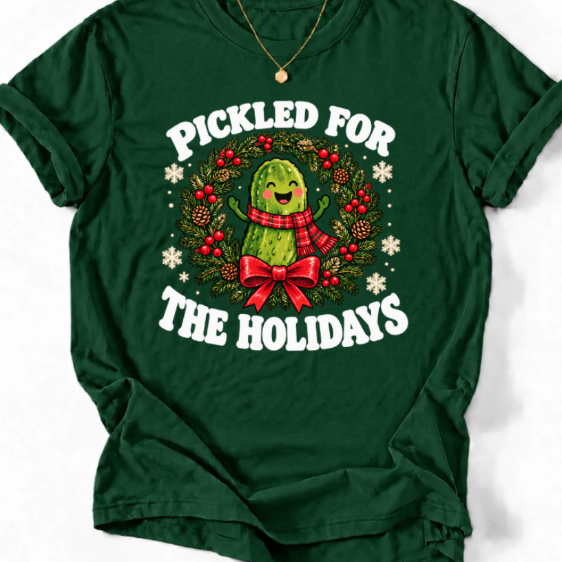 Forest green ‘Pickled for the Holidays’ T-shirt with a smiling pickle in a red scarf inside a Christmas wreath.”