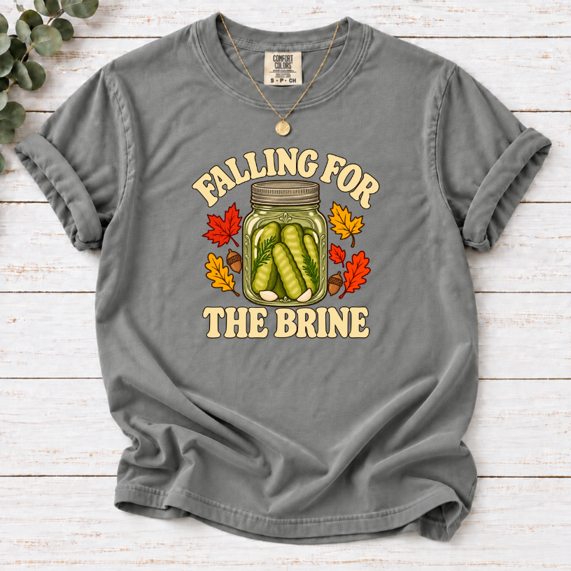 Grey T-shirt with “Falling for the Brine” lettering and a pickle jar surrounded by autumn leaves and acorns.
