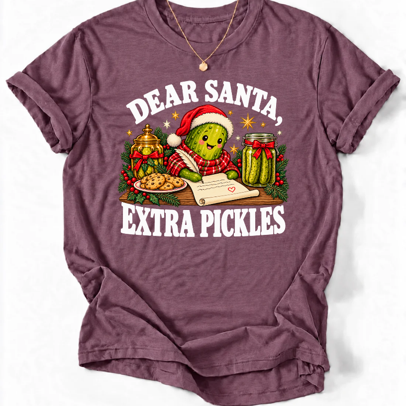 Heather Maroon ‘Dear Santa, Extra Pickles’ T-shirt featuring a Santa-hat pickle writing a letter beside cookies and pickles.”