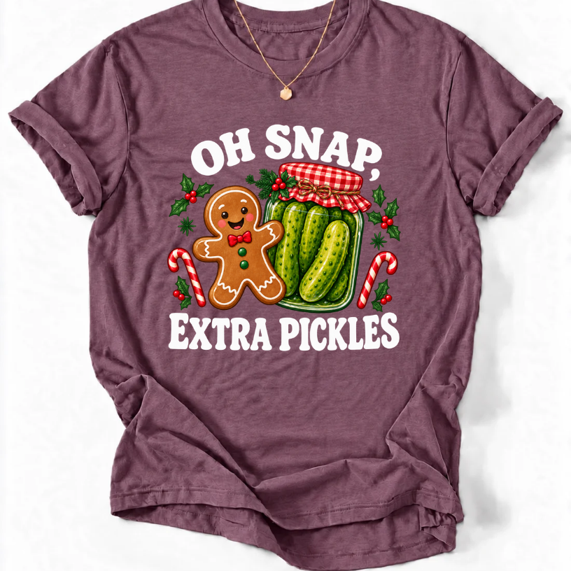 Heather Maroon T-shirt with “Oh Snap, Extra Pickles” lettering, a smiling gingerbread character, and a pickle jar surrounded by candy canes and holly.
