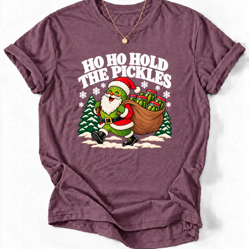 Heather Maroon T-shirt with “Ho Ho Hold the Pickles” lettering and a pickle dressed as Santa carrying a sack of pickle jars beside snowy trees.