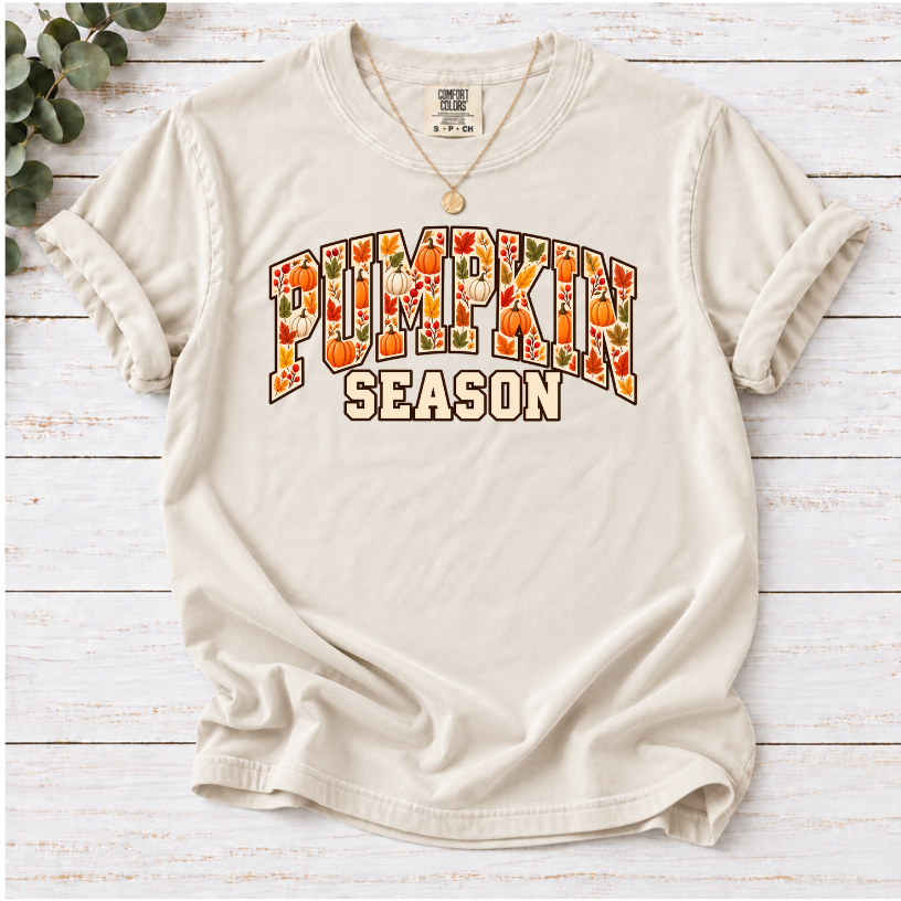 Ivory T-shirt with Pumpkin Season lettering filled with orange and white pumpkins and autumn leaves.