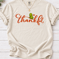 Ivory T-shirt with thankful script, a smiling green pickle, and a small orange heart.