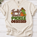 Ivory T-shirt with ‘Thankful Blessed & Pickle Obsessed’ lettering and a pilgrim-hat pickle hugging a pumpkin