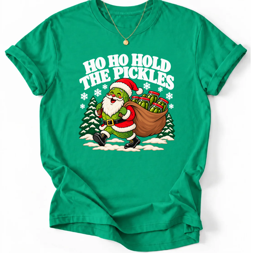 Kelly Green T-shirt with “Ho Ho Hold the Pickles” lettering and a pickle dressed as Santa carrying a sack of pickle jars beside snowy trees.