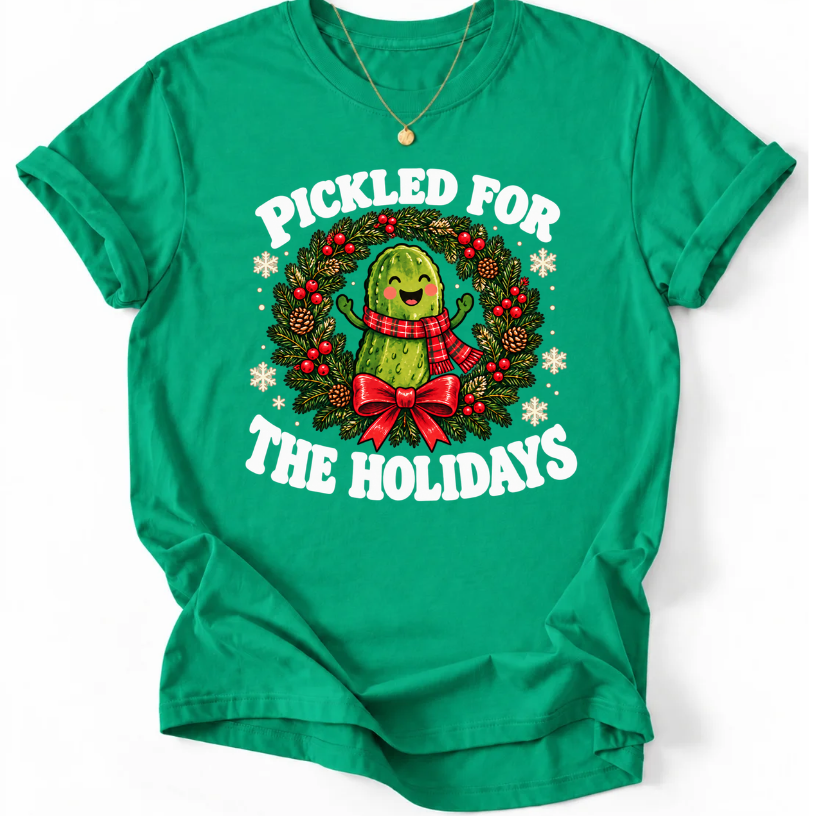 Kelly Green Pickled for the Holidays’ T-shirt with a smiling pickle in a red scarf inside a Christmas wreath.”