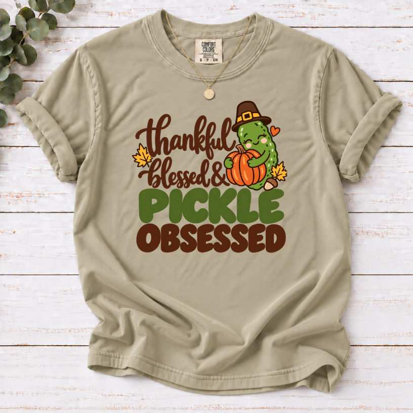 Khaki  T-shirt with ‘Thankful khaki Blessed & Pickle Obsessed’ lettering and a pilgrim-hat pickle hugging a pumpkin