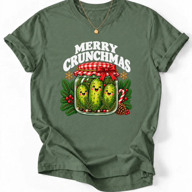 Military Green T-shirt with “Merry Crunchmas” lettering above three smiling pickles in a jar decorated with a red bow and Christmas greenery.